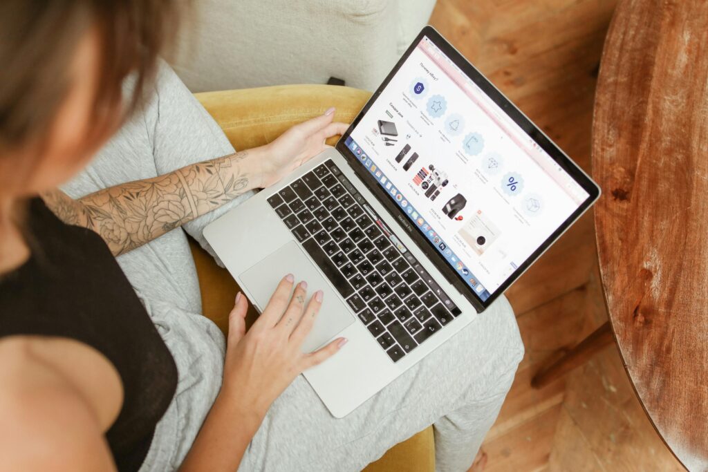 Woman with tattoos browsing online shopping site on a laptop indoors